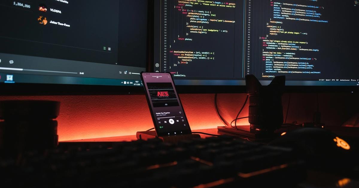 a cell phone is sitting on a desk in front of a computer monitor .